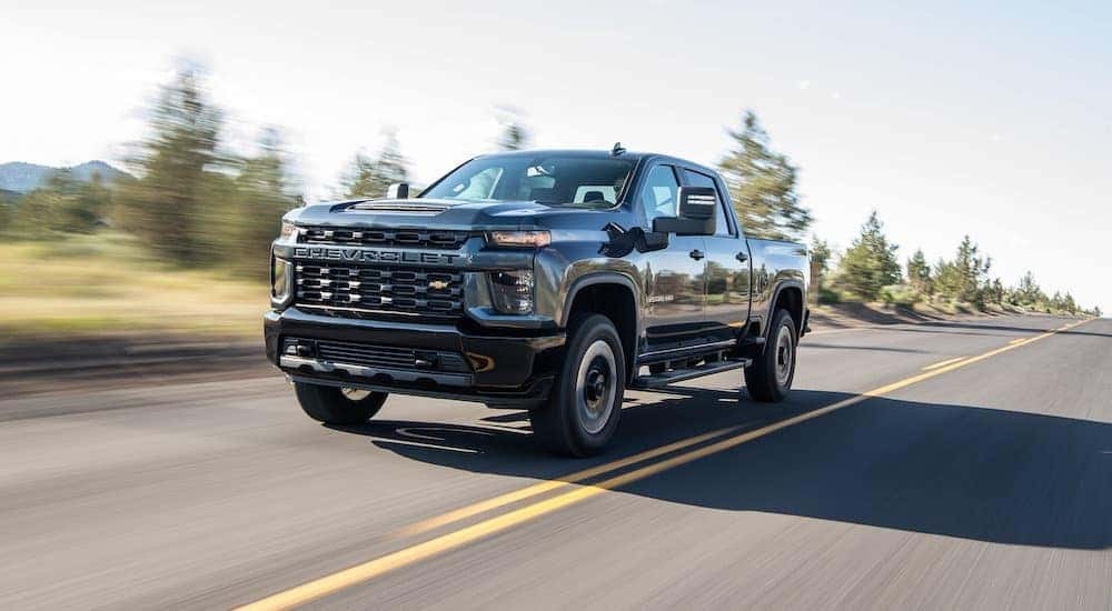 Black 2020 Chevy Silverado 2500HD, is shown driving on a highway.