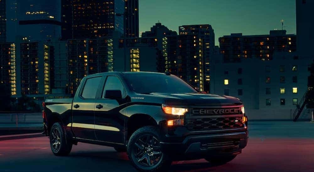 A black 2024 Chevy Silverado 1500 Custom is shown parked at night.