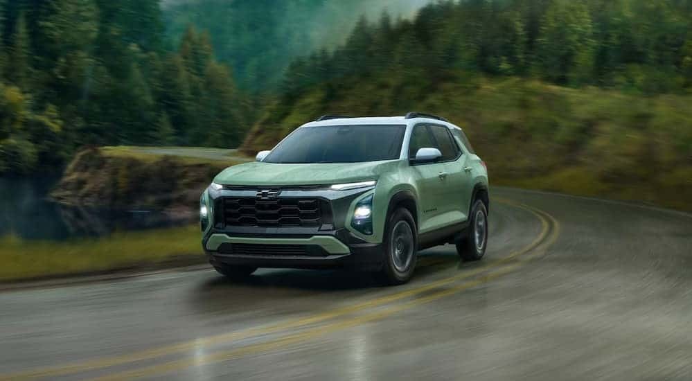 A green 2025 Chevy Equinox ACTIV driving on a rainy day.