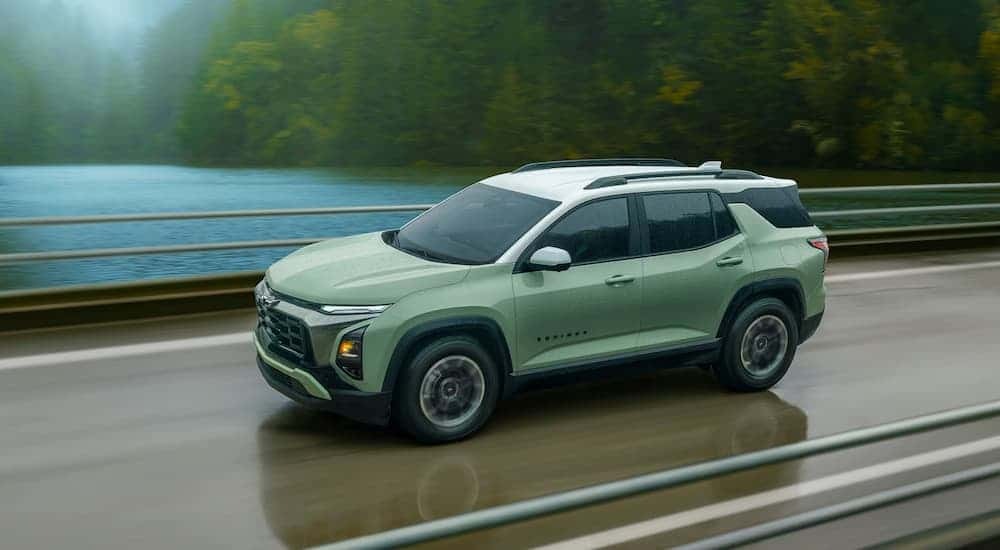 A green 2026 Chevy Equinox ACTIV driving down a road