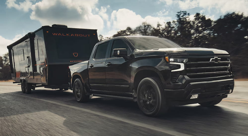 Black 2026 Chevy Silverado 1500 towing a camper van.