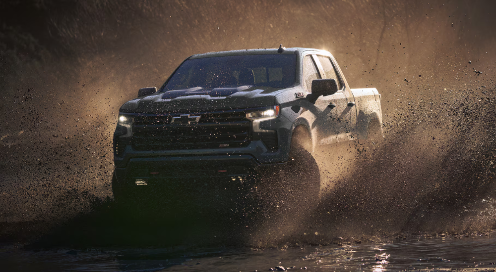 A blue 2026 Chevy Silverado 1500 off-roading in mud
