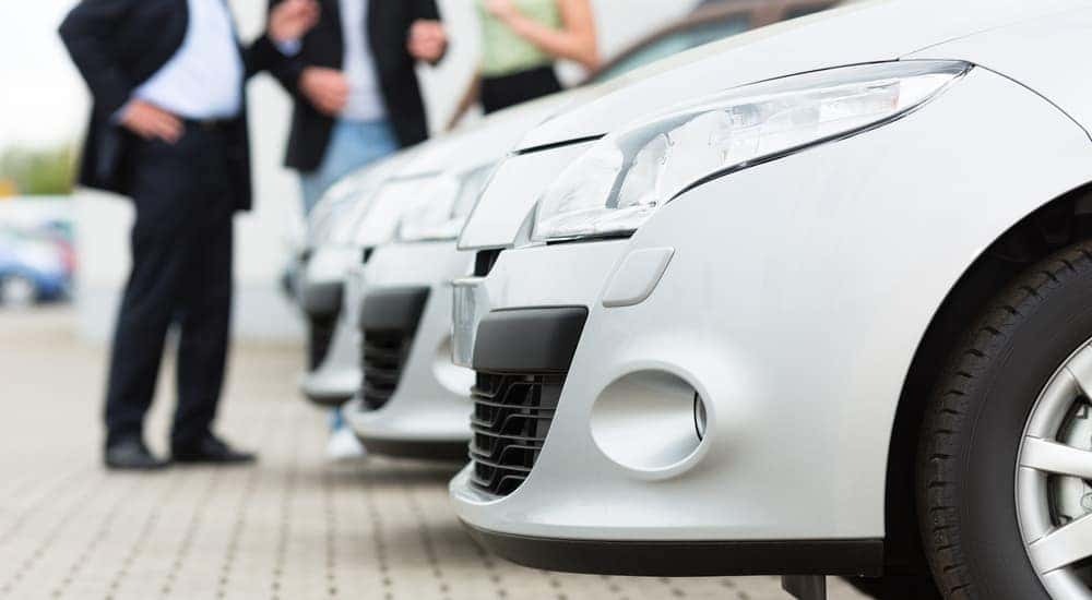 A row of white cars are shown parked at a dealership.
