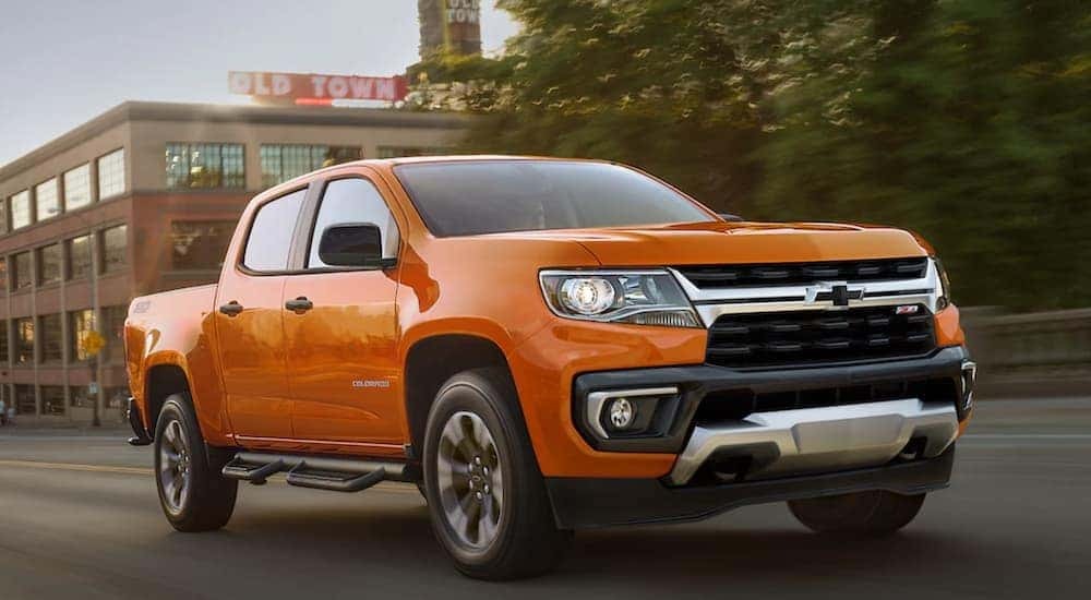 An orange 2021 Chevy Colorado Z71 is shown on a city street after searching for used Chevy trucks for sale.