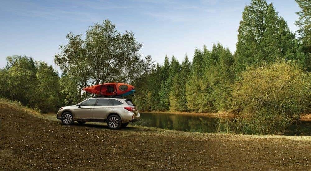 A silver 2016 Subaru Outback is shown near a lake.