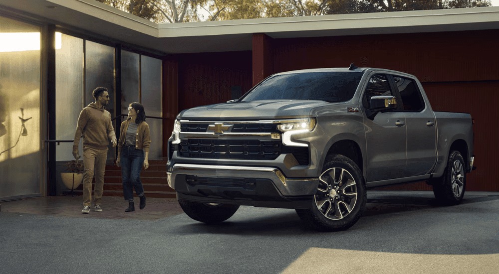 A couple walking up to their silver 2026 Chevy Silverado 1500