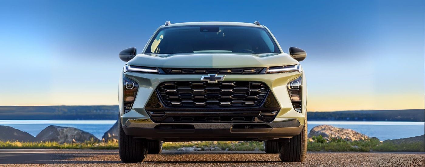 A green 2024 Chevy Trax parked head-on by a lake.