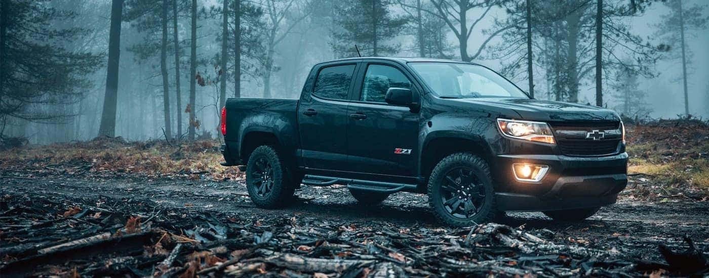 A black 2018 Chevy Colorado Z71 is shown on a trail in the woods after leaving a Chevy truck dealer near me.