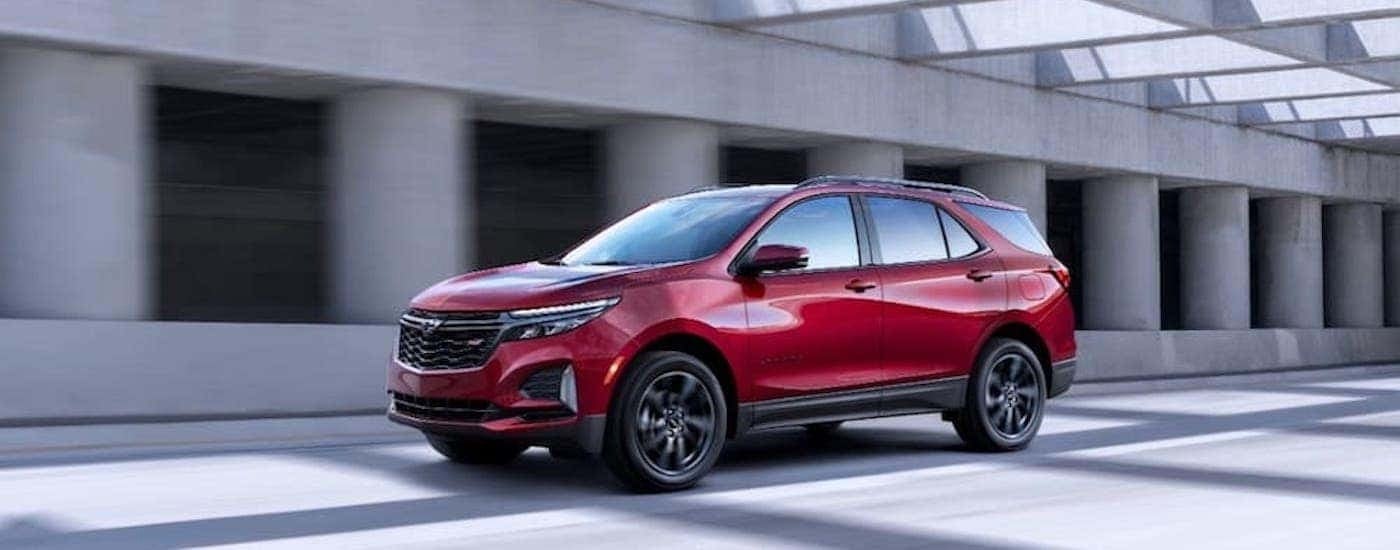 A red 2022 Chevy Equinox RS driving to look at used Chevy SUVs for sale