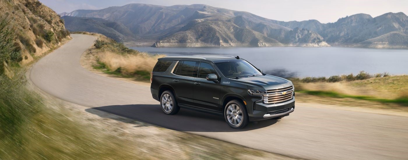 Black 2024 Chevy Tahoe High Country driving past a lake