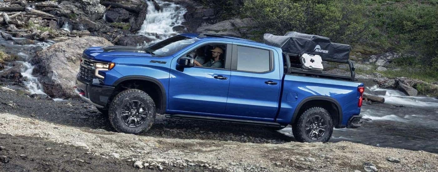 A blue 2024 Chevy Silverado 1500 ZR2 off-roading near a river