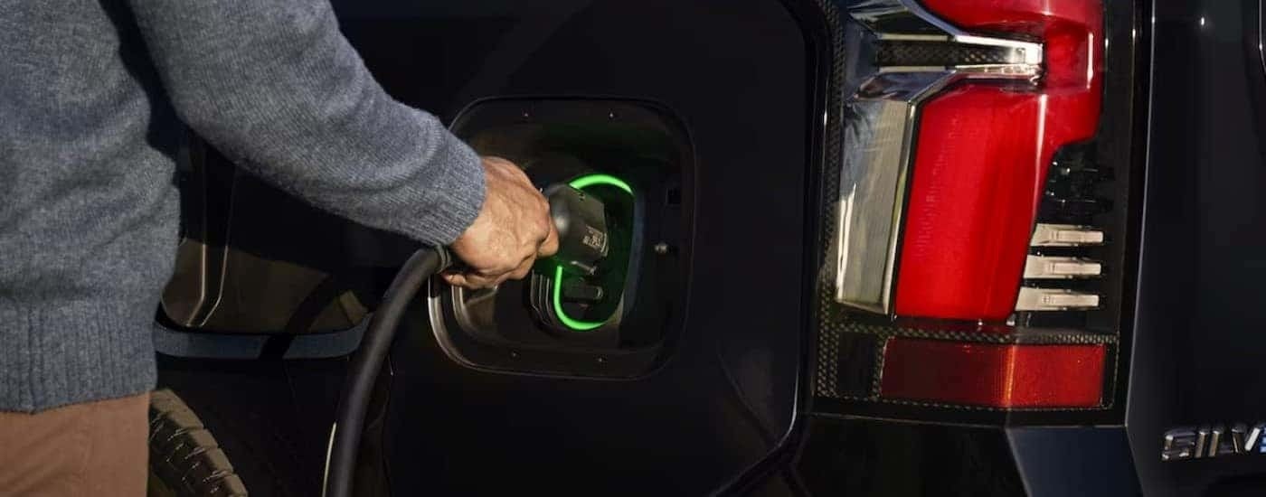 A person is shown charing a 2024 Chevy Silverado EV.