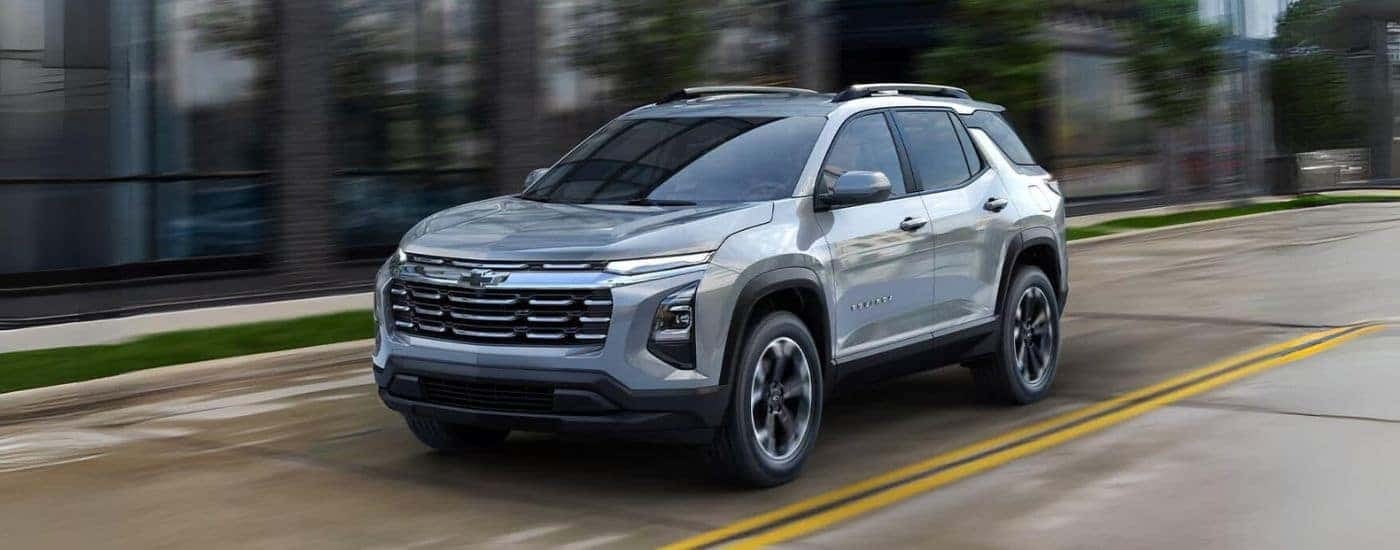 A silver 2025 Chevy Equinox driving down a city street