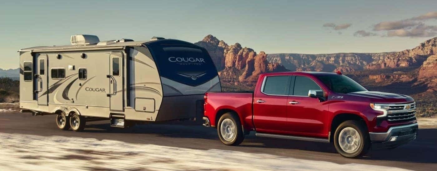 A red 2026 Chevy Silverado 1500 towing a trailer.