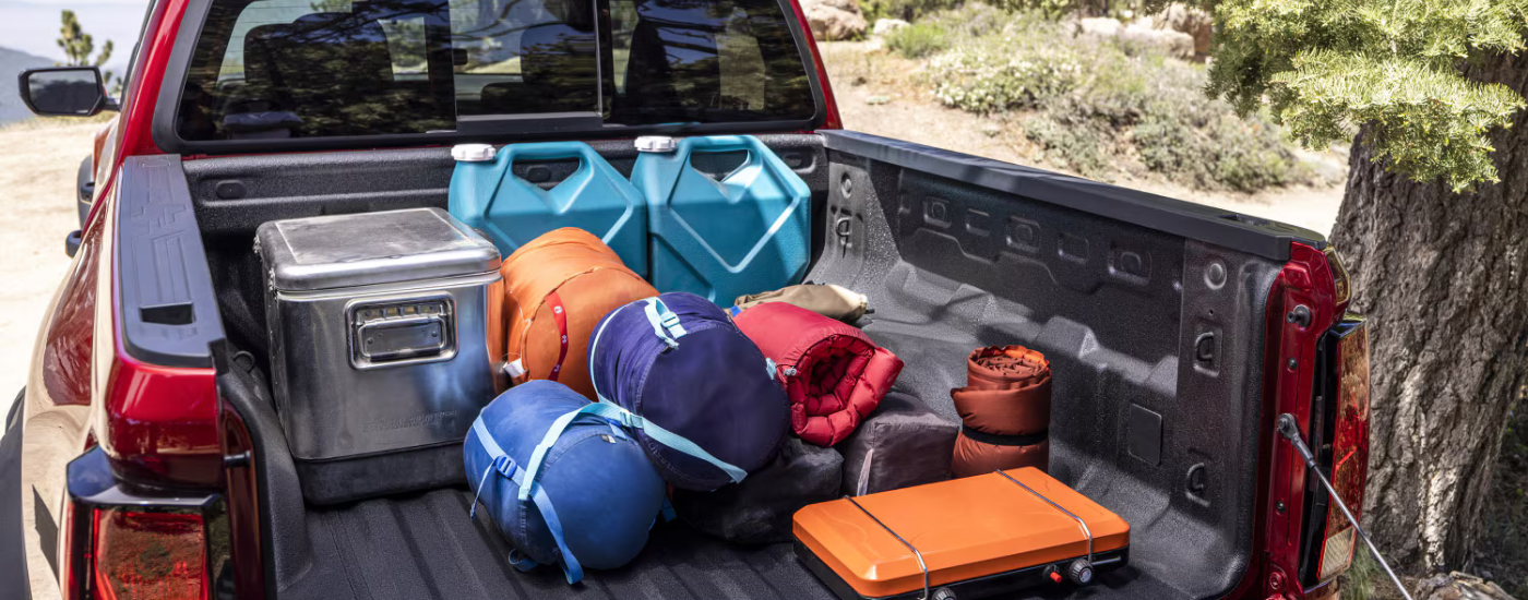 Camping gear loaded in the bed of a red 2024 Chevy Colorado Trail Boss.