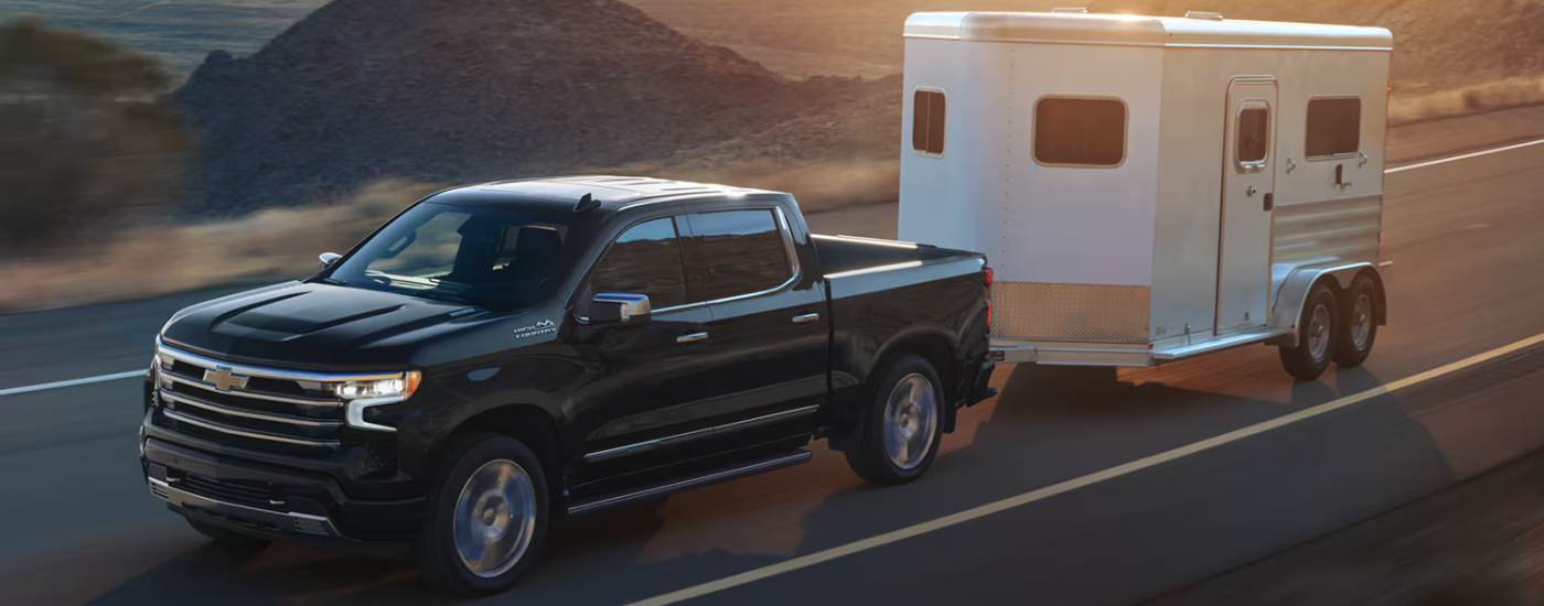 Black 2026 Chevy Silverado 1500 towing a horse trailer