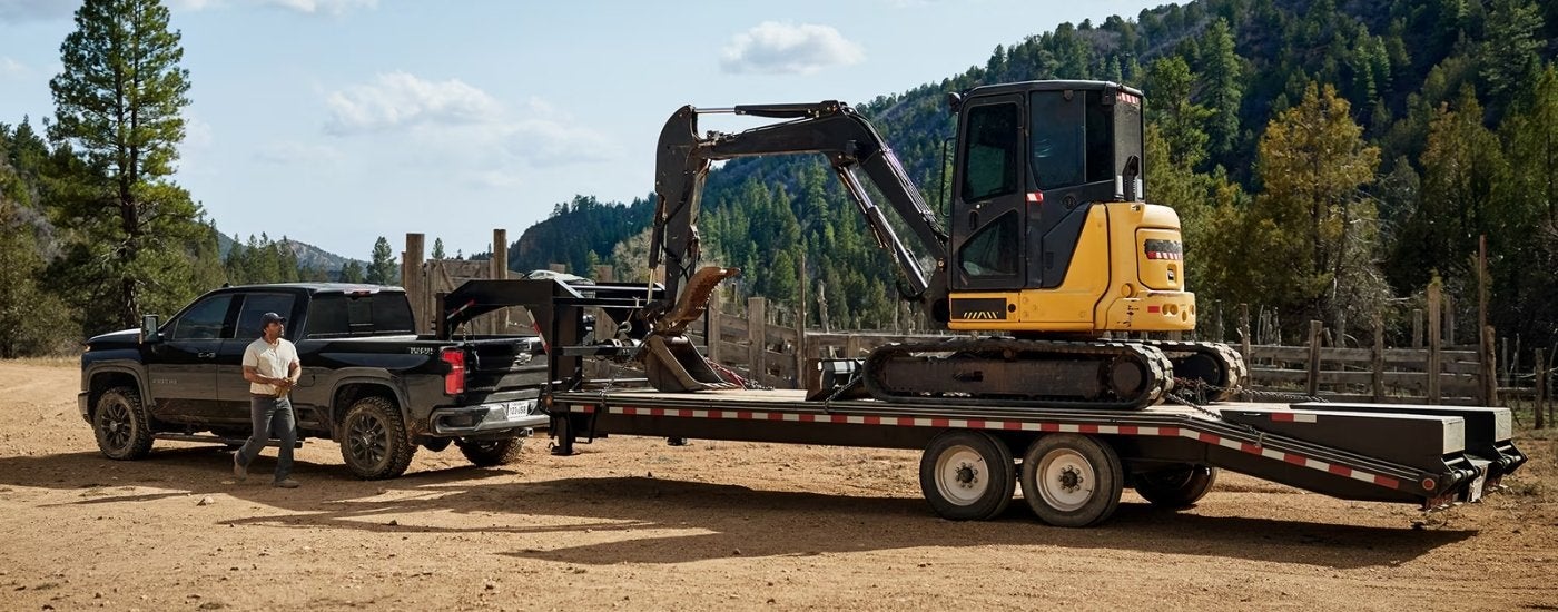 Black 2026 Chevy Silverado 2500 HD LTZ Trail Boss towing an excavator