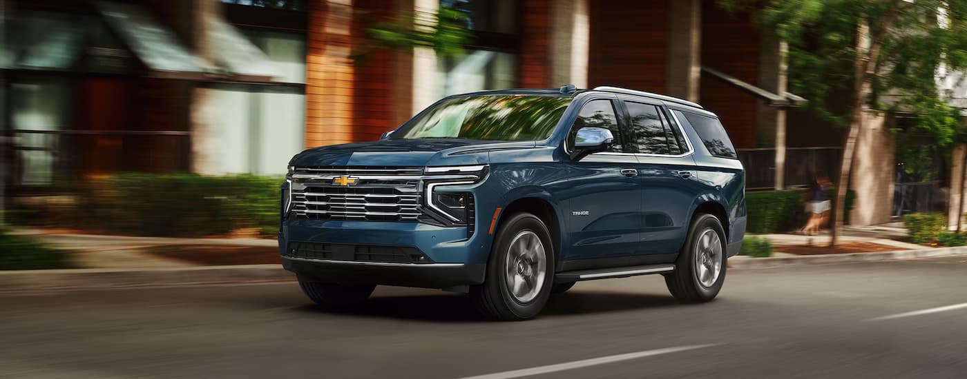 Blue 2026 Chevy Tahoe driving down a city street.