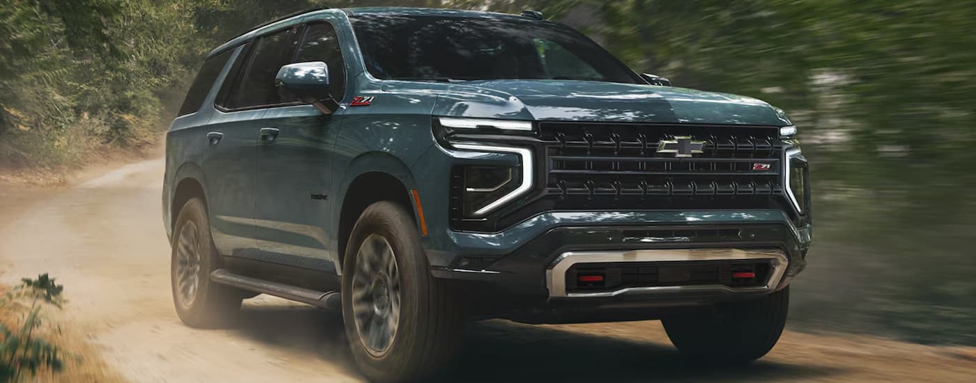 Blue 2026 Chevy Tahoe driving off-road on a dirt road.