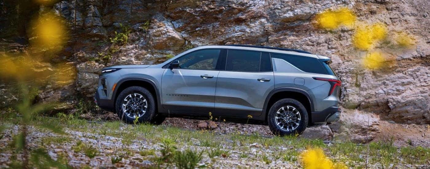 Side of a silver 2024 Chevy Traverse Z71 parked off-road near a flower field.