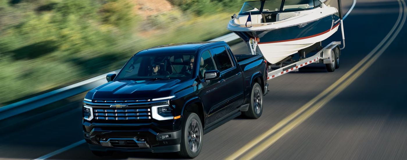A black 2027 Chevy Silverado1500 High Country towing a boat.