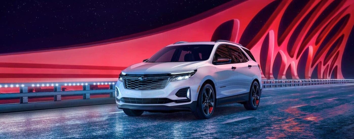 White 2023 Chevy Equinox driving to a Chevrolet dealer
