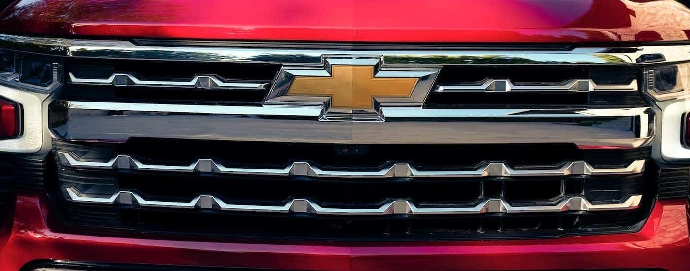 A close up of the silver grille on a red 2023 Chevy Silverado 1500 LTZ.