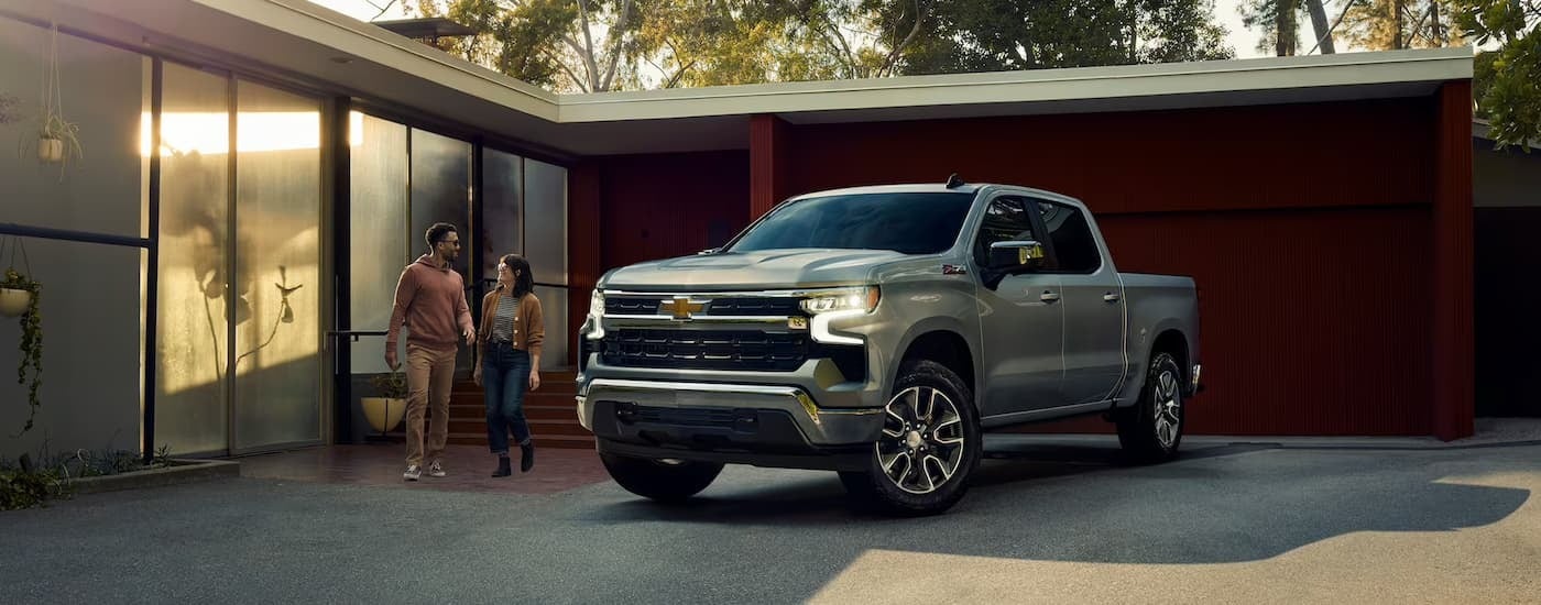 A silver 2023 Chevy Silverado 1500 Z71 is shown parked on a driveway near a house.