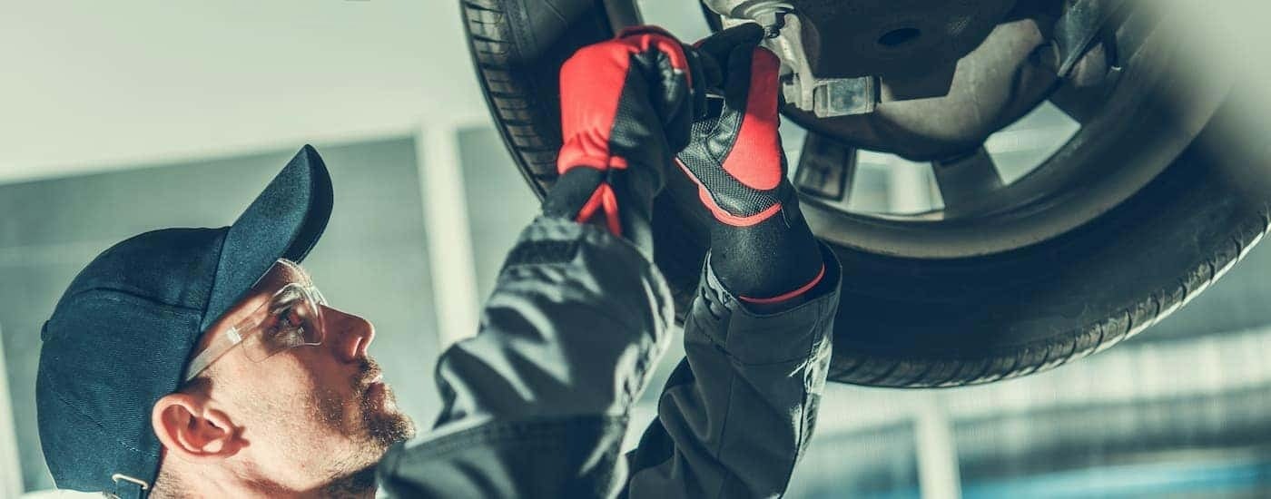 A mechanic is shown working on a vehicle on a lift.