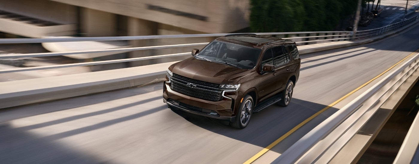 Brown 2023 Chevy Tahoe driving to a used Chevrolet dealer